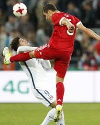 Two soccer players colliding as they try to get the ball.